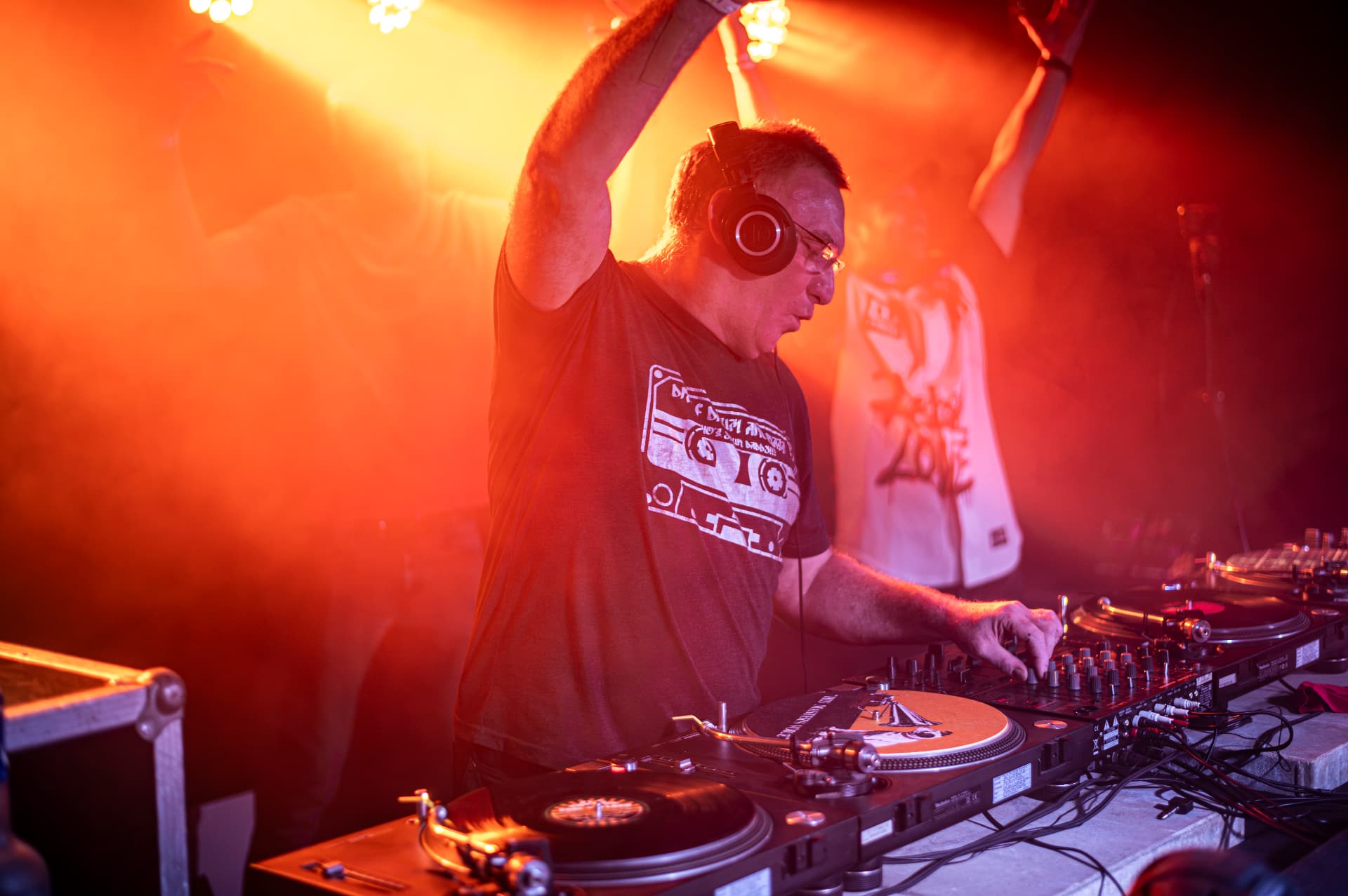 DJ se zdviženou rukou v oranžovém světle