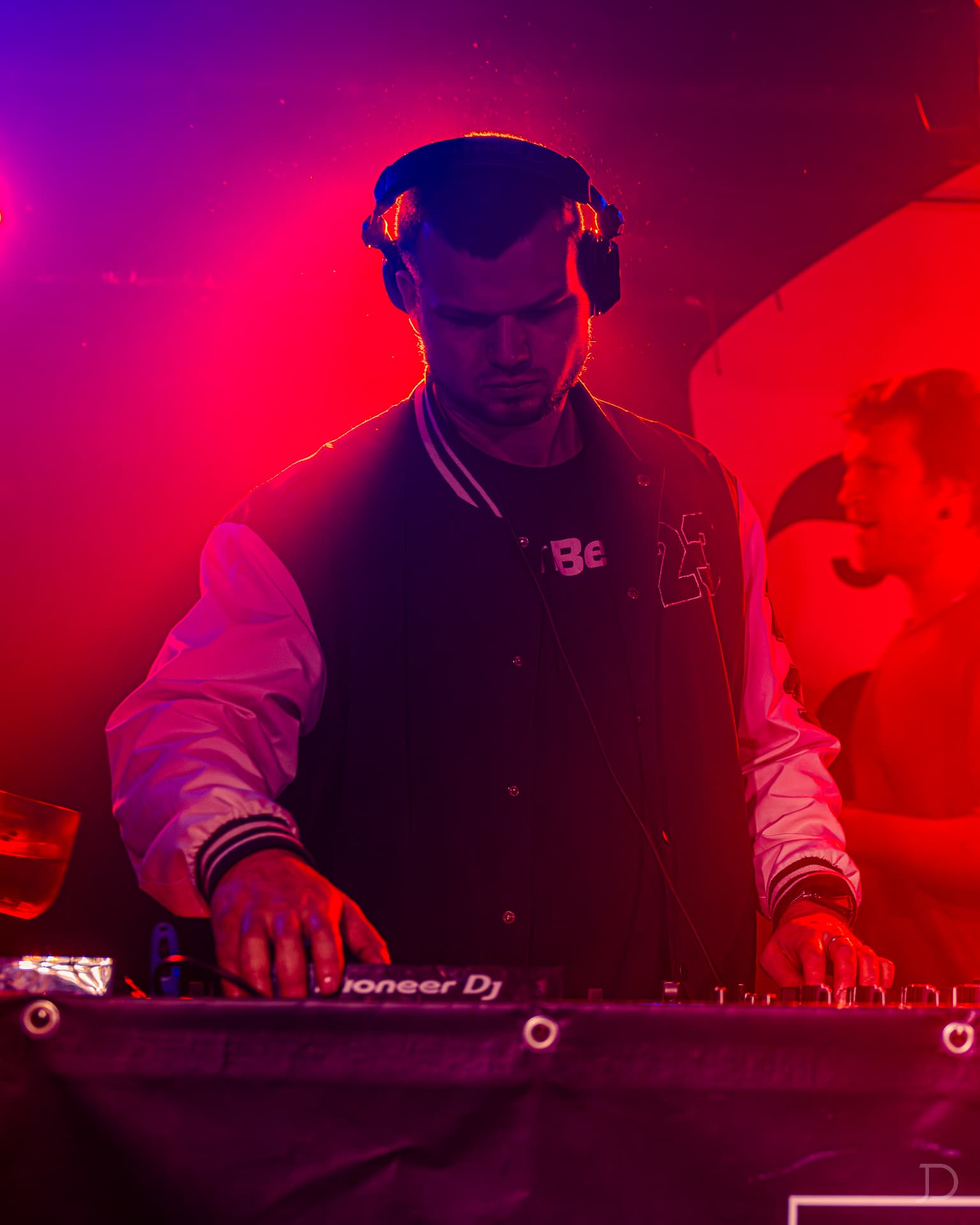 DJ za Pioneer mixem v červeno-fialovém světle