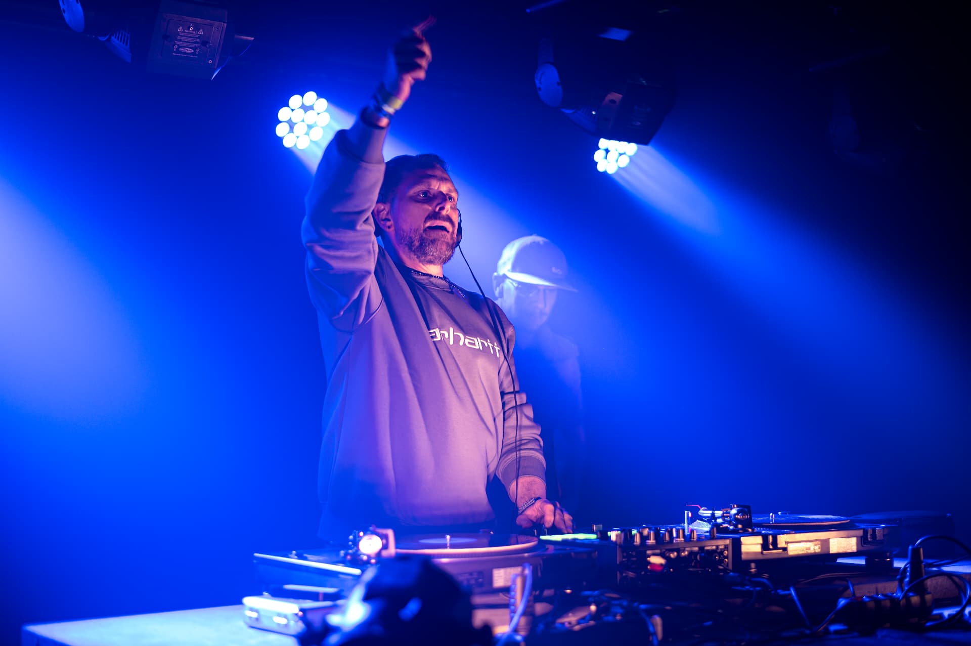 DJ se zdviženou rukou v modrém světle