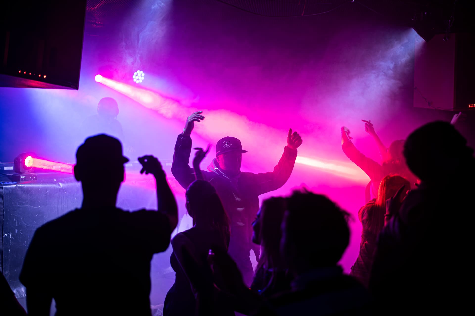 Tančící dav v růžovo-fialovém světle a kouři na party