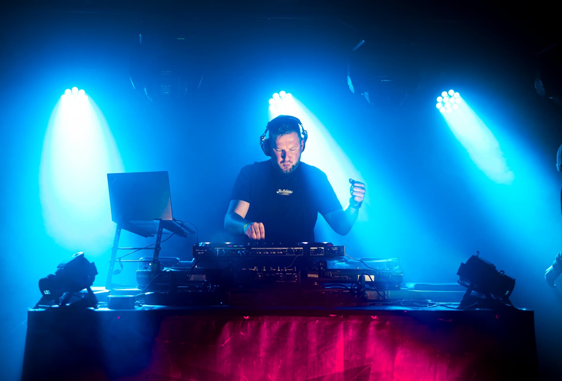 DJ za mixem v modrých světlech a kouři