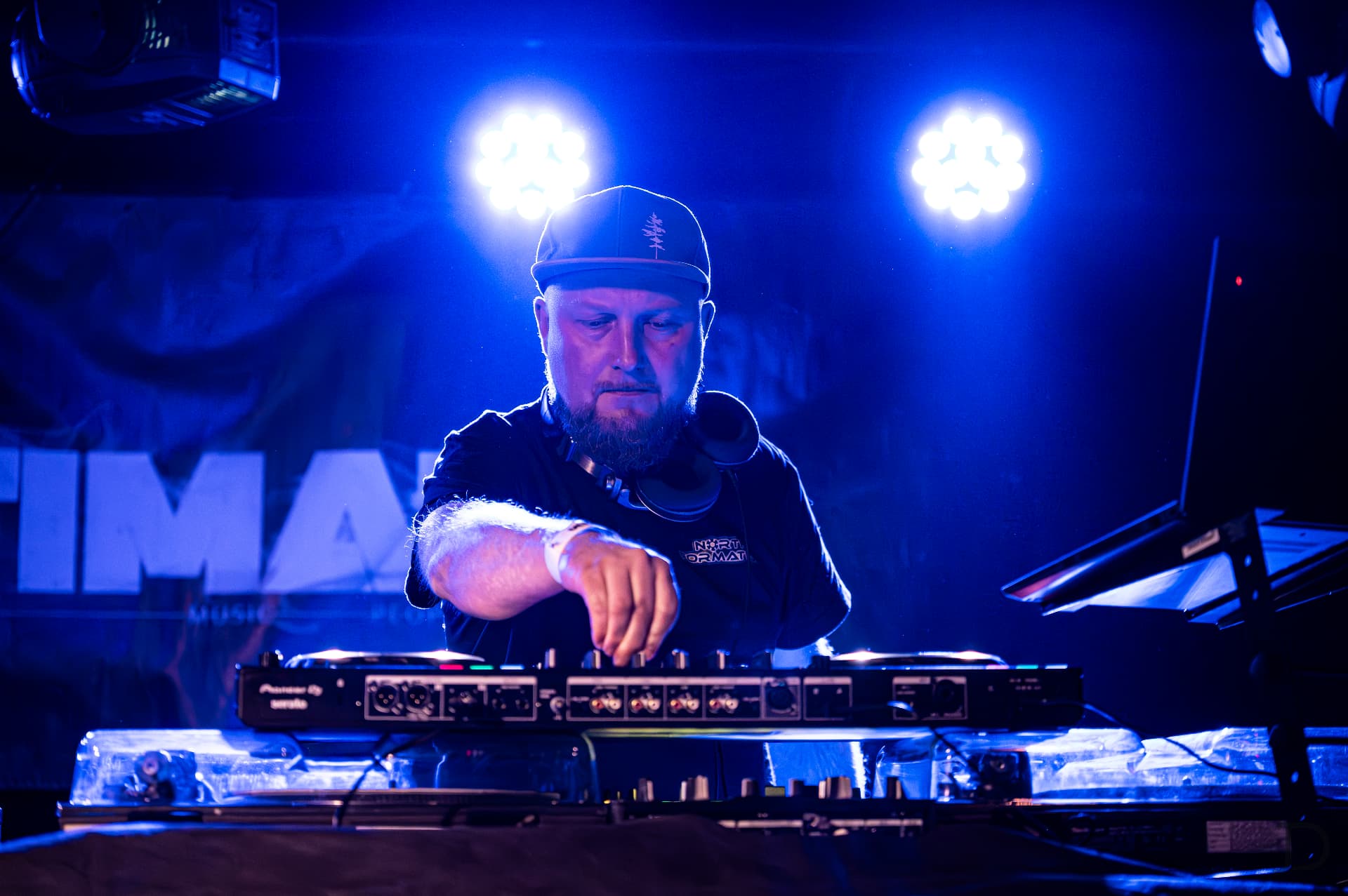DJ v kšiltovce za Pioneer mixem v modrém světle
