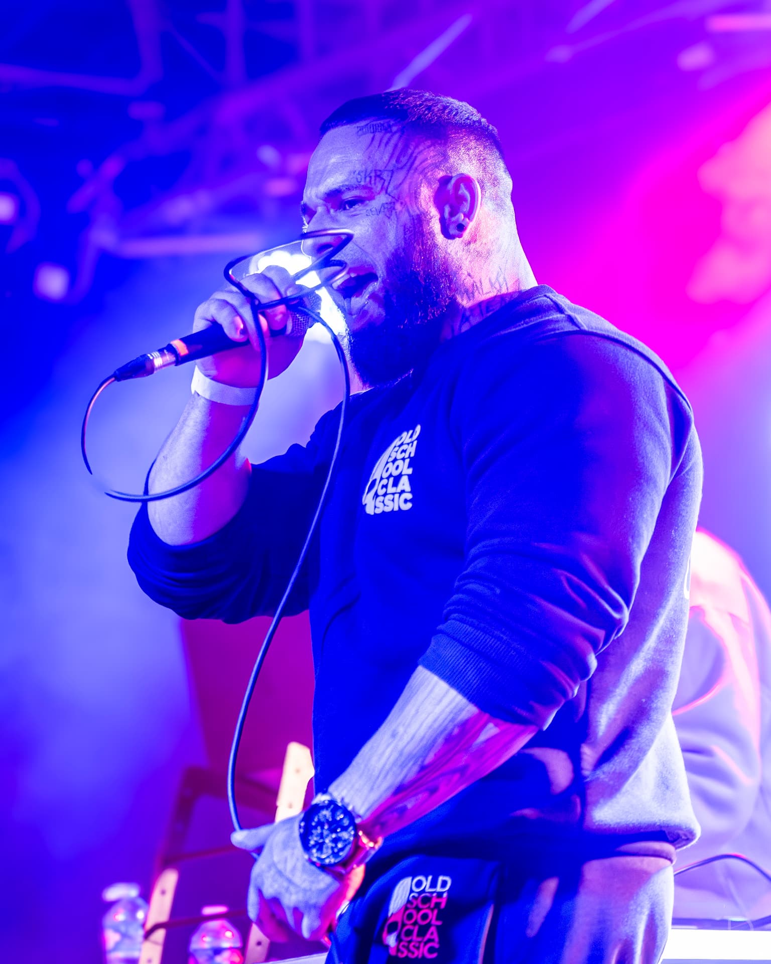 Rapper zpívající do mikrofonu v modrofialovém světle